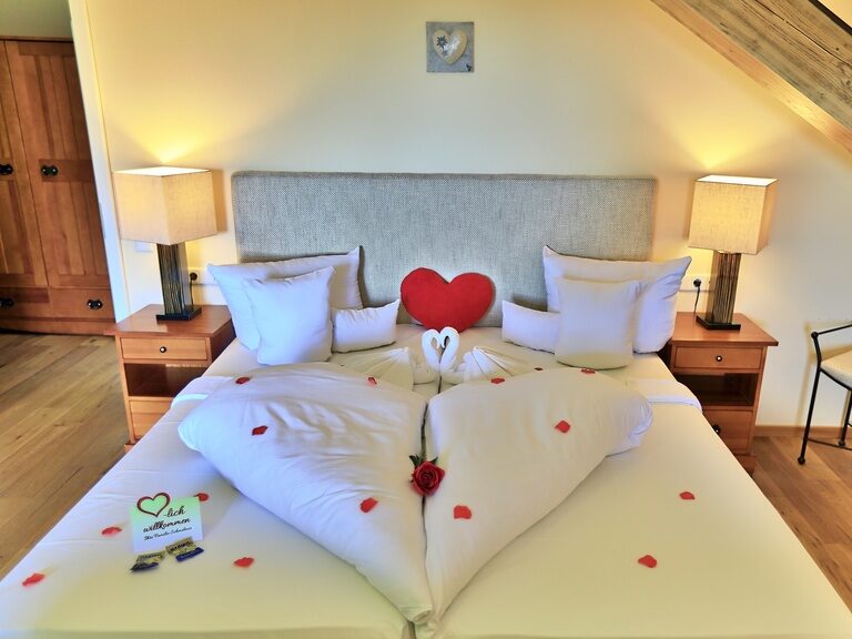 Ein romantisch angerichtetes Bett im Hotel Gut Schmelmerhof in Sankt Englmar.